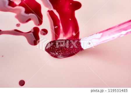 Vibrant red lip gloss with brush on pink background 119531485