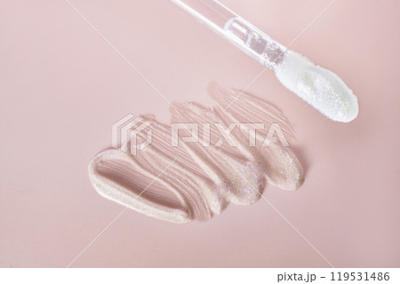 Shimmering nude lip gloss with applicator on pink background 119531486