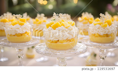 Elegant mango parfait desserts with whipped cream and edible flowers on glass stands 119531697
