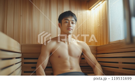 Relaxed young asian man enjoying sauna session in modern wooden sauna room 119531699
