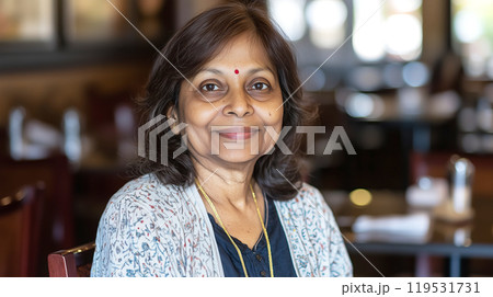 Smiling elderly Indian woman in restaurant setting with traditional attire 119531731