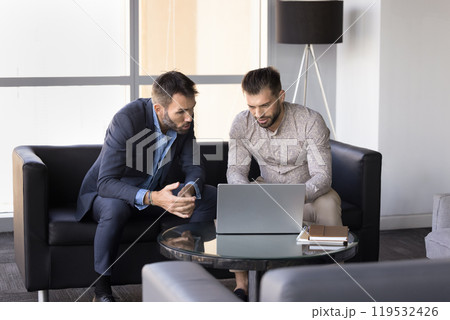 Two focused male business colleagues discussing job application Two focused male business colleagues discussing job application 119532426