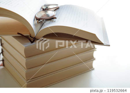 読書の秋のイメージ 積み重ねられた本の上に開かれた本とメガネ、モックアップ 読書の秋のイメージ 積み重ねられた本の上に開かれた本とメガネ、モックアップ 119532664