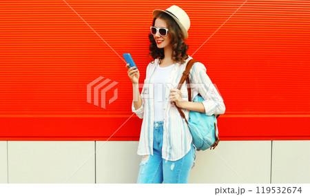 happy smiling young woman with smartphone in summer hat with backpack on red background happy smiling young woman with smartphone in summer hat with backpack on red background 119532674