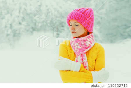 winter happy woman wearing colorful hat, sweater, scarf enjoys over snowy forest or park background 119532713