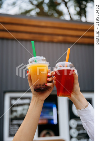 Hands raising colorful bubble teas, symbolizing joyful moments and refreshing street beverages 119533452