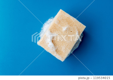 foam sponge for washing dishes on blue ceramic table, copy space. foam sponge for washing dishes on blue ceramic table, copy space. 119534015