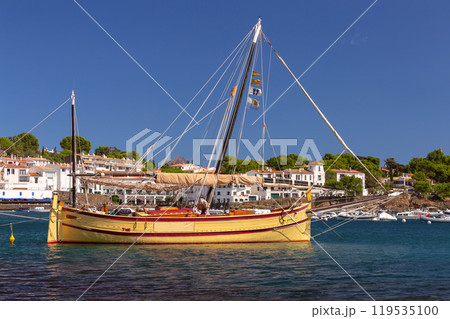 A large yellow fishing sailboat in the harbour of Cadaques. 119535100