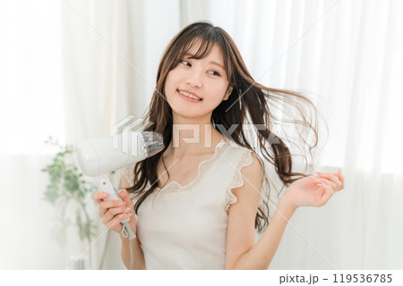 ヘアドライヤーでヘアブロー・髪の毛を乾かす女性（ヘアケア） 119536785