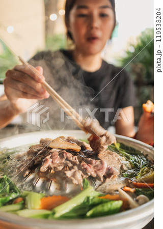 Happy woman enjoy her delicious Thai BBQ Buffet. 119538204