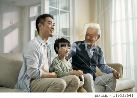 asian son father grandfather watching soccer game on TV together at home 119538641