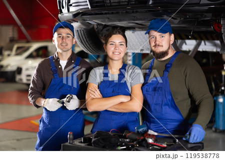 Two guys and woman mechanics posing at car service station Two guys and woman mechanics posing at car service station 119538778