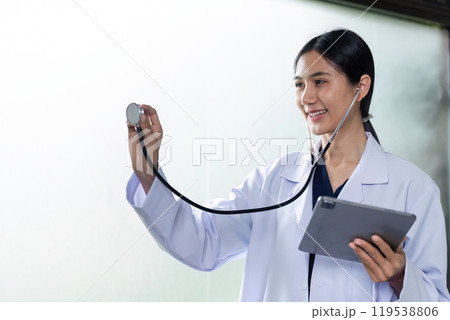Female Doctor Performing Examination Gesture with Stethoscope in Modern Medical Setting Female Doctor Performing Examination Gesture with Stethoscope in Modern Medical Setting 119538806