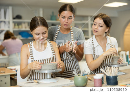 Female teacher explaining to students how to sculpt ceramics 119538950