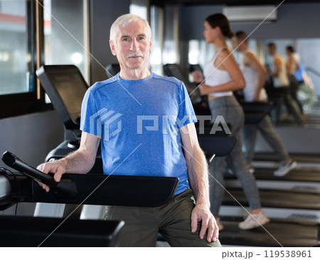 Portrait of elderly man running on treadmill in sport gym Portrait of elderly man running on treadmill in sport gym 119538961