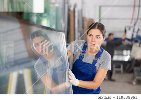Female employee pushing A-frame with insulated glass units at factory 119538963