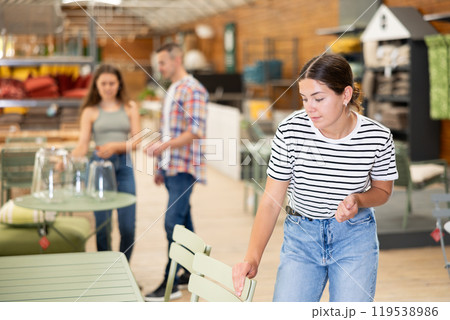 Girl buyer choose chair in garden furniture store showroom Girl buyer choose chair in garden furniture store showroom 119538986