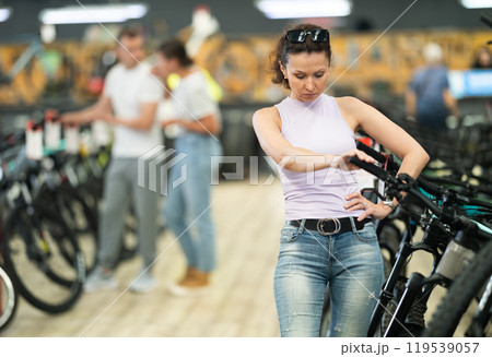 Woman thoughtfully comparing bicycle handlebar system in shop Woman thoughtfully comparing bicycle handlebar system in shop 119539057