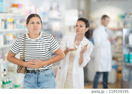 Female pharmacist offering headache medicine to customer in pharmacy Female pharmacist offering headache medicine to customer in pharmacy 119539195