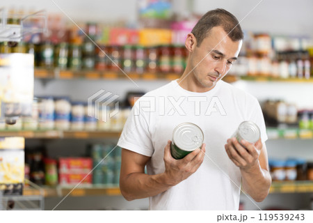 In supermarket store, man choose jar of canned food 119539243