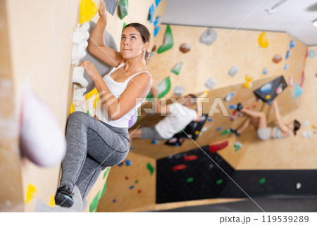 Young girl moving on bouldering wall at indoor climbing gym 119539289