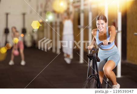 Young woman exercising on exercise bike in gym 119539347