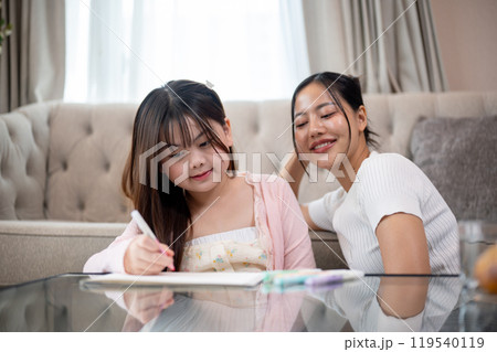 A caring and kind Asian mom is teaching her daughter to draw, enjoying quality family time together. 119540119