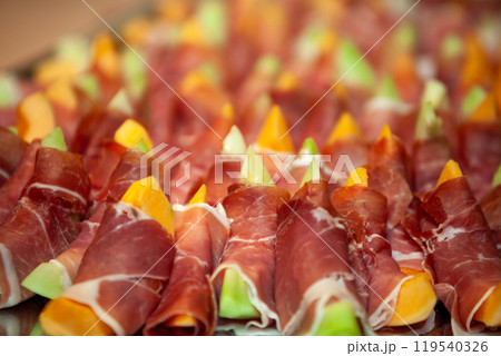 Savor the flavor of these exquisite Prosciutto Wrapped Melon Bites for your elegant catering needs 119540326
