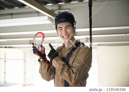 ハーネスをつける現場作業員　「高所作業もご安全に！」のポーズ 119540396