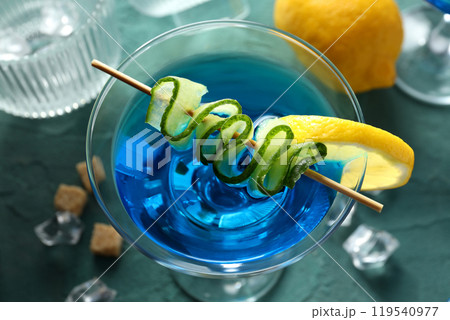 Blue cocktail with lemon and cucumber slices on green background, close up Blue cocktail with lemon and cucumber slices on green background, close up 119540977