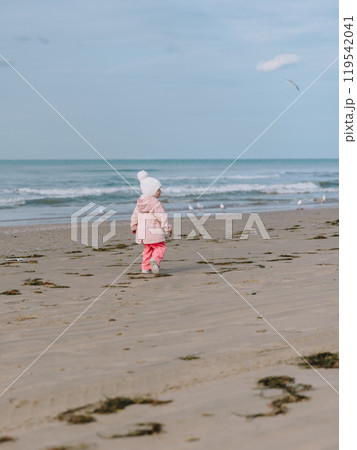 Little child girl walk on ocean coastline. Winter concept. 119542041