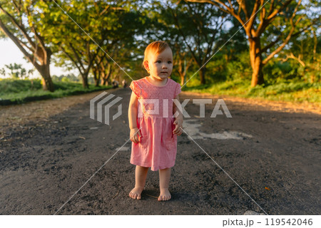 Little child girl. Cute baby staying in park with sunset light. 119542046