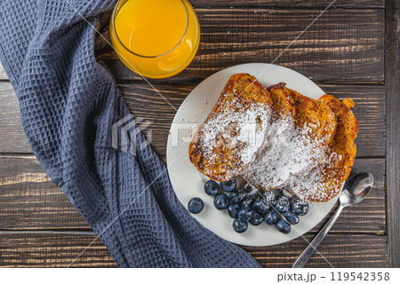 French toast on a white plate with blueberries and orange juice for breakfast 119542358