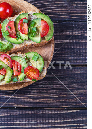 Avocado toast topped with tomato and green onion on a slice of carrot bread 119542420
