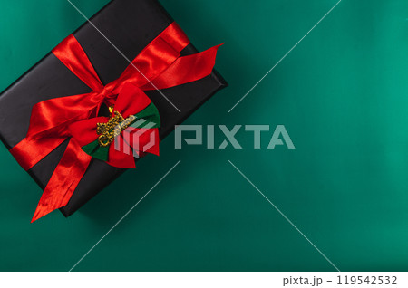 Gift box with red bow and Merry Christmas, on green background Gift box with red bow and Merry Christmas, on green background 119542532
