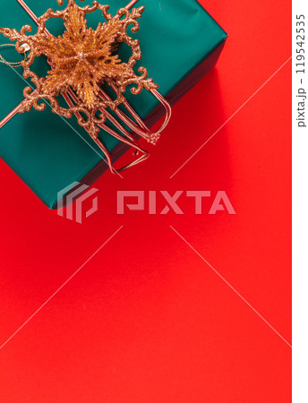 Dark green Christmas gift box with gold star decoration on red background Dark green Christmas gift box with gold star decoration on red background 119542535