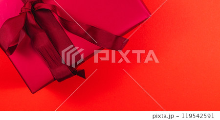 banner Red gift box with dark red bow and ribbon on red background 119542591