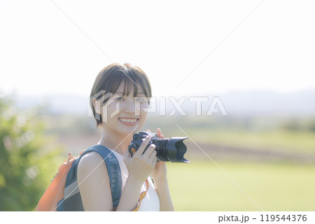 草原でカメラを構える若い女性 草原でカメラを構える若い女性 119544376