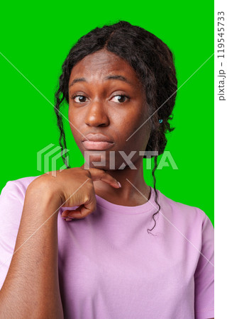 Thoughtful woman pondering in front of a bright green background during a casual moment 119545733