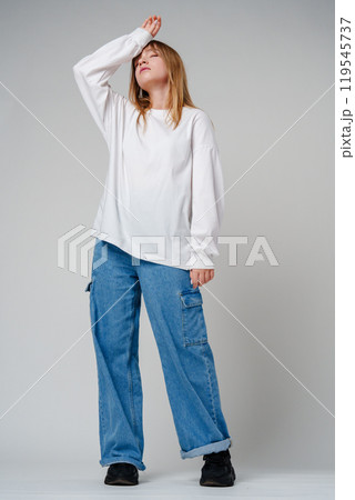 A young woman in a white long-sleeve shirt expressing a moment of contemplation against a neutral background A young woman in a white long-sleeve shirt expressing a moment of contemplation against a neutral background 119545737