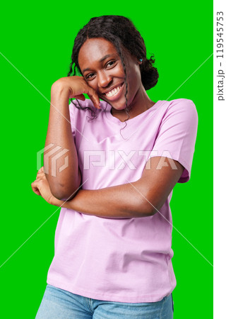 Happy young person laughing and playfully covering face while standing against a bright green background 119545753