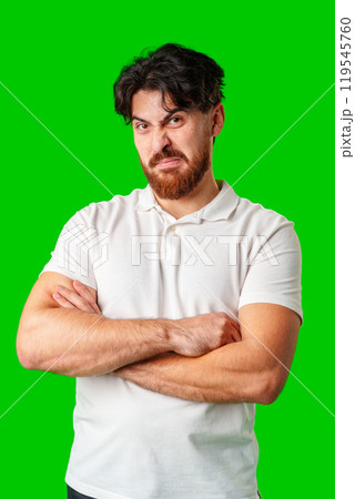 A man makes a funny face while posing against a bright green background 119545760