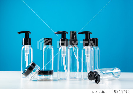Clear plastic bottles with black caps arranged on a white surface against a bright blue background Clear plastic bottles with black caps arranged on a white surface against a bright blue background 119545790