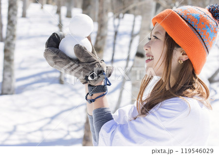 スキー場で小さい雪だるまを作って眺める若い女性 スキースノーボードイメージ スキー場で小さい雪だるまを作って眺める若い女性 スキースノーボードイメージ 119546029