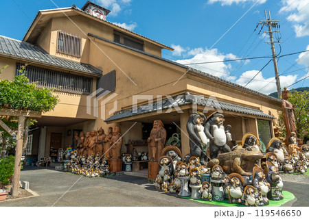 滋賀県甲賀市信楽町のたぬきの陶器の置物を並べて販売しているお店の店先 119546650