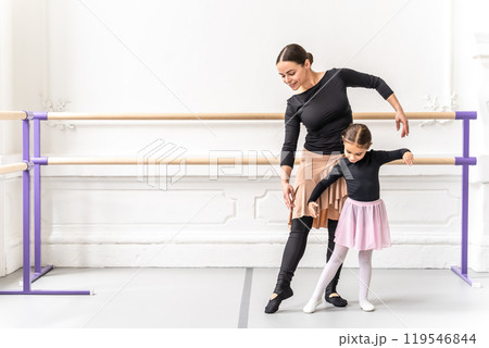Happy ballerina teacher guiding young student in graceful ballet practice 119546844