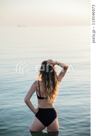 Beautiful woman in black swimsuit relaxing on the beach 119546973