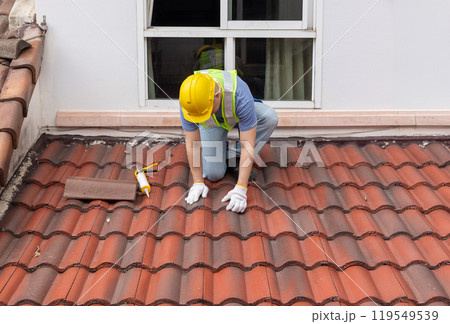 Construction worker is inspecting roof tile cracked. Construction worker is inspecting roof tile cracked. 119549539