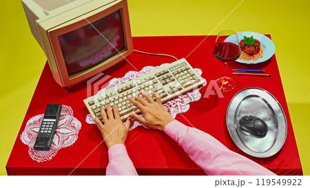 Close-up of hand using computer mouse placed on silver platter, with spaghetti resting on keyboard. Image mixes work and food in strange way. 119549922