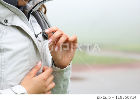 Trekker zipping up jacket in the mountain a foggy day Trekker zipping up jacket in the mountain a foggy day 119550714